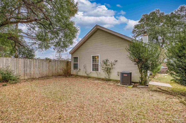 view of side of home with cooling unit and a yard