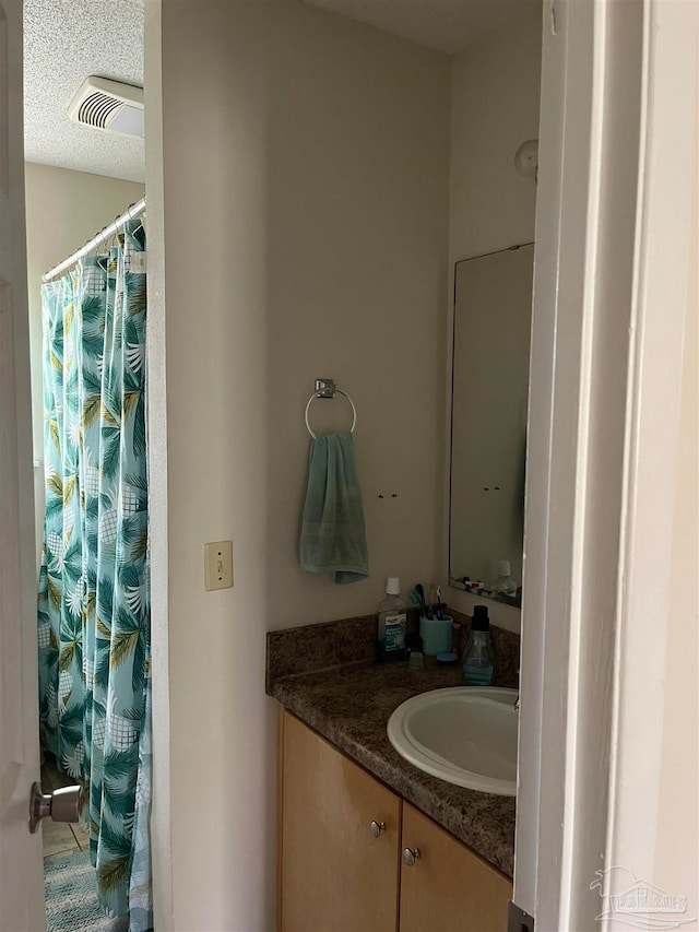 bathroom featuring a shower with curtain, vanity, and a textured ceiling