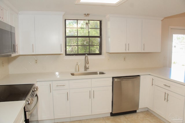 kitchen featuring sink, light tile patterned floors, appliances with stainless steel finishes, tasteful backsplash, and white cabinetry