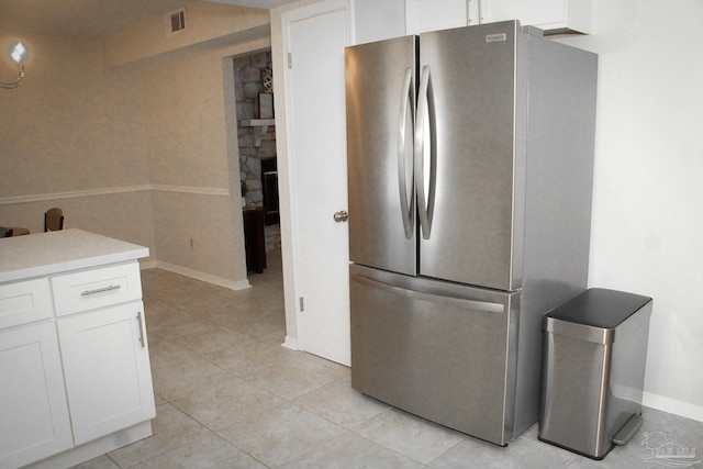 kitchen featuring stainless steel fridge, white cabinetry, and light tile patterned floors