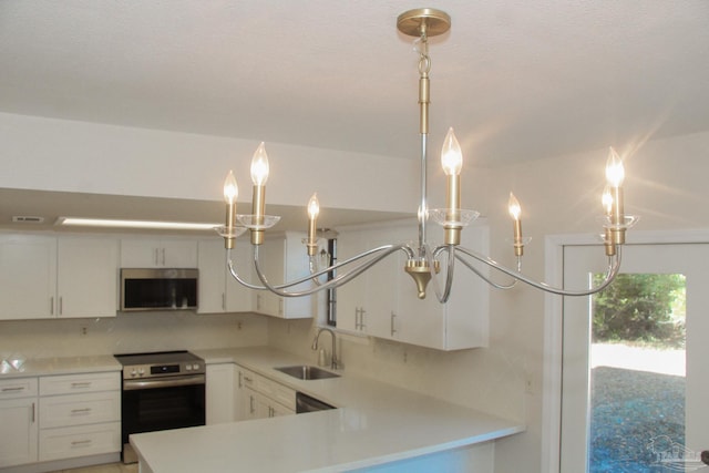 kitchen with white cabinets, appliances with stainless steel finishes, decorative light fixtures, and sink