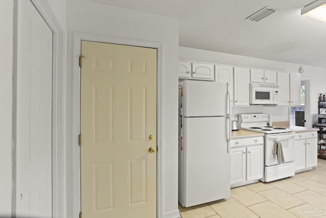 kitchen with white cabinetry, white appliances, a textured ceiling, and light tile patterned floors