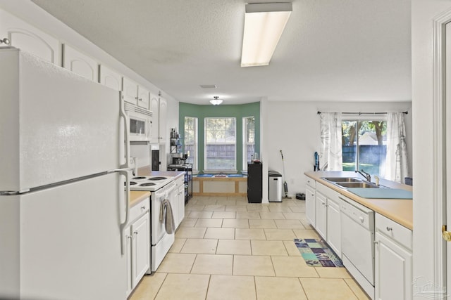 kitchen with white cabinetry, sink, light tile patterned floors, and white appliances