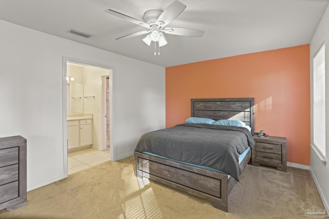 bedroom featuring connected bathroom, ceiling fan, and light colored carpet