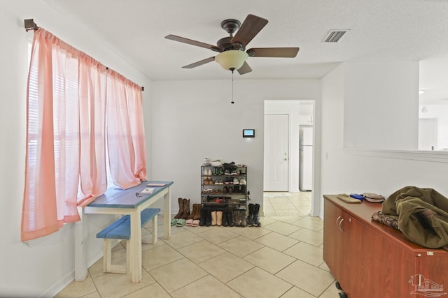 interior space featuring ceiling fan, light tile patterned flooring, and a textured ceiling