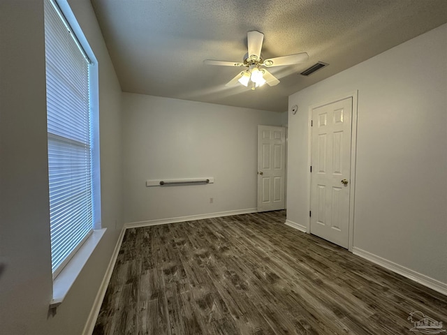 4885 Mayo Cir, Pace, FL 32571 - unfurnished bedroom featuring dark wood finished floors, multiple windows, baseboards, a textured ceiling, and a ceiling fan