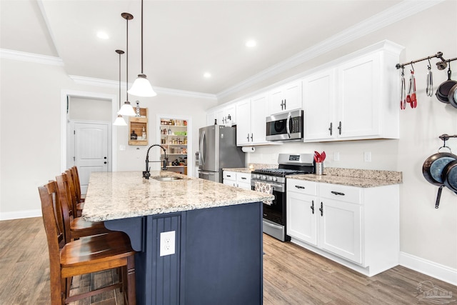 kitchen with stainless steel appliances, a kitchen island with sink, sink, light hardwood / wood-style floors, and hanging light fixtures