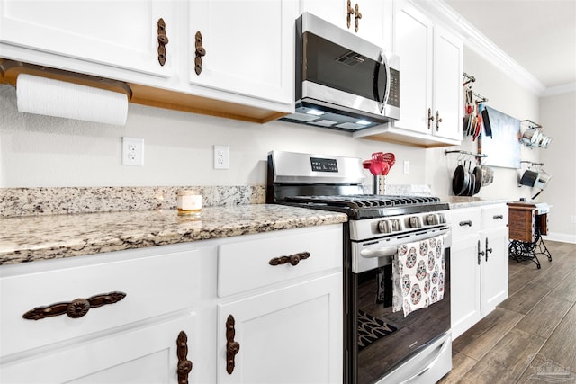 kitchen featuring light stone countertops, white cabinetry, stainless steel appliances, dark hardwood / wood-style floors, and crown molding