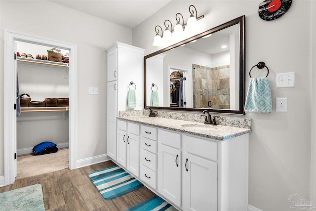 bathroom with a shower with shower door, wood-type flooring, and vanity