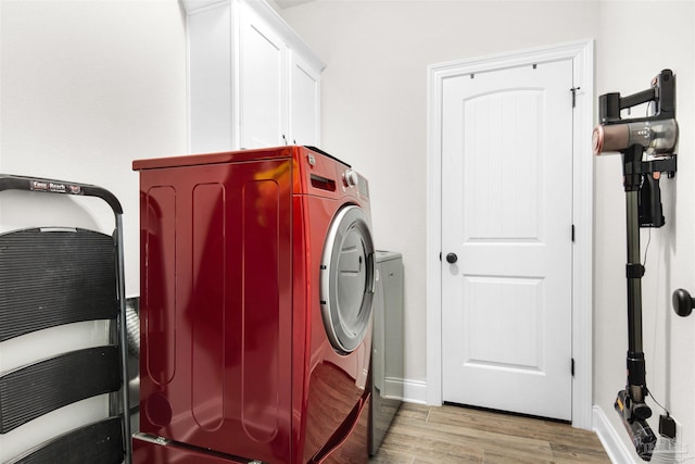 washroom with cabinets, washer and dryer, and light wood-type flooring