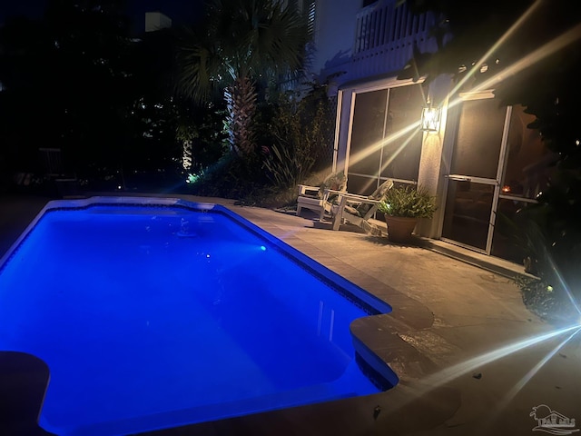 pool at twilight featuring a patio area