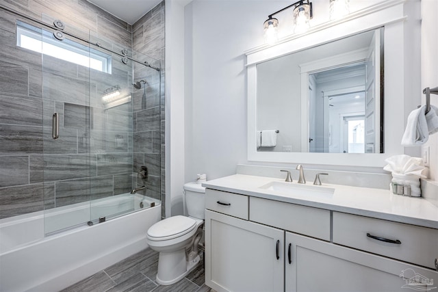 full bathroom featuring bath / shower combo with glass door, toilet, and vanity