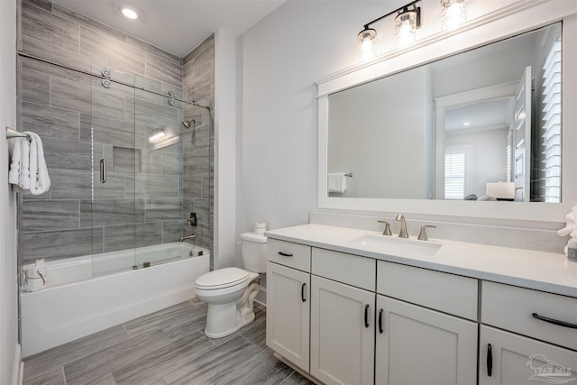 full bathroom featuring toilet, vanity, and shower / bath combination with glass door