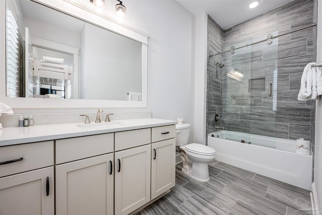 full bathroom featuring toilet, combined bath / shower with glass door, and vanity