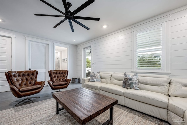 living room featuring ceiling fan, a healthy amount of sunlight, and wood walls