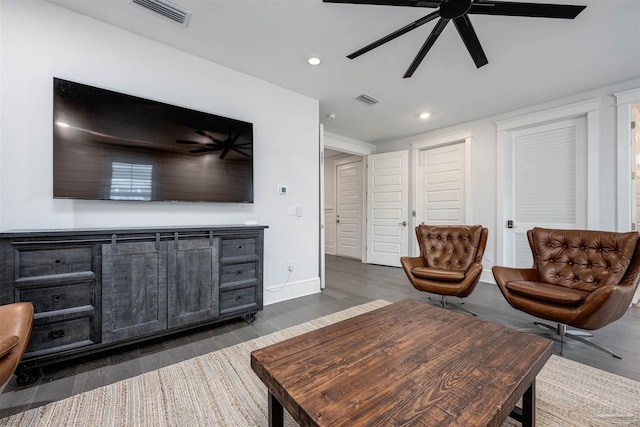 living room featuring ceiling fan and dark wood-type flooring