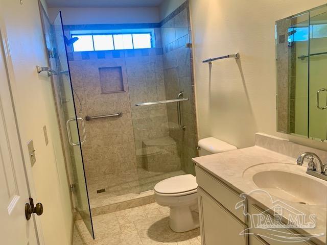 bathroom featuring vanity, toilet, a shower with door, and tile patterned floors