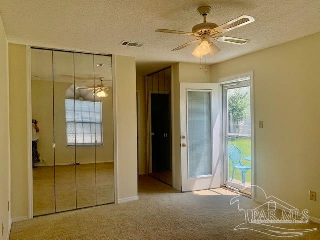 unfurnished bedroom with a textured ceiling, ceiling fan, and carpet flooring