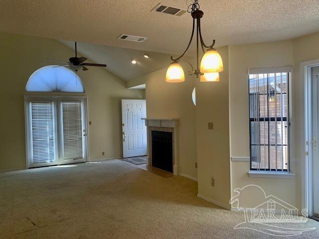 unfurnished living room featuring a textured ceiling, lofted ceiling, light colored carpet, and ceiling fan