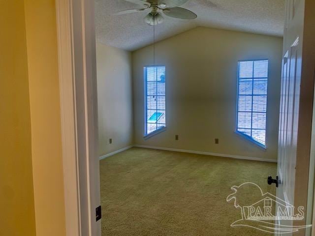 carpeted empty room featuring ceiling fan, lofted ceiling, and a textured ceiling