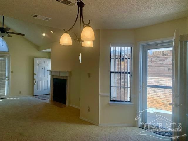 unfurnished living room with ceiling fan with notable chandelier, lofted ceiling, a wealth of natural light, and light colored carpet