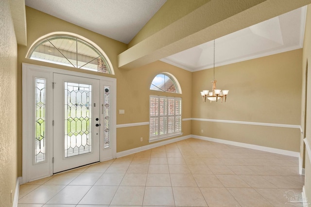 tiled entrance foyer featuring ornamental molding, a textured ceiling, and a notable chandelier