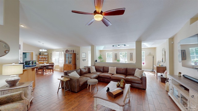 living room featuring hardwood / wood-style floors, ceiling fan with notable chandelier, and vaulted ceiling