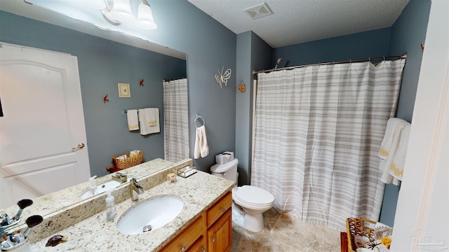 bathroom featuring tile patterned flooring, vanity, a textured ceiling, and toilet