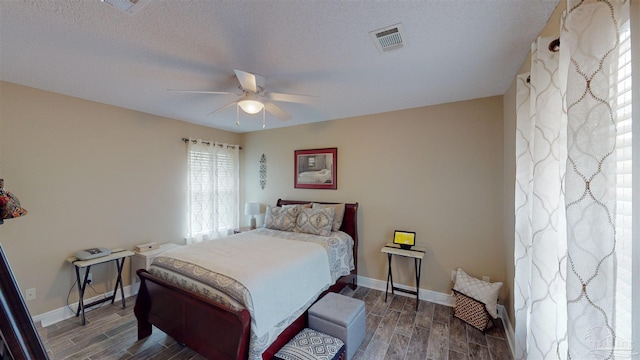 bedroom with a textured ceiling, ceiling fan, and dark hardwood / wood-style floors