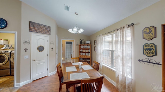 dining area with independent washer and dryer, vaulted ceiling, a notable chandelier, and hardwood / wood-style floors