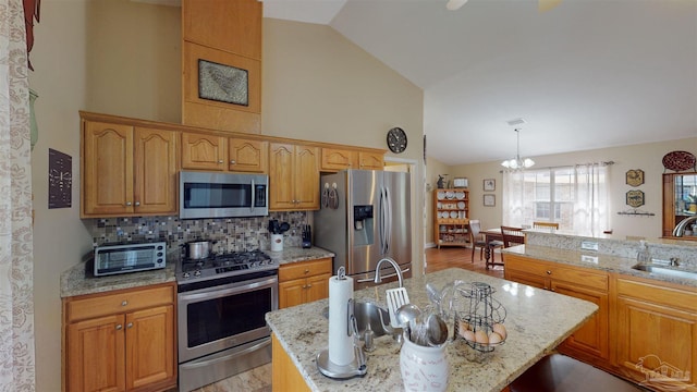 kitchen with a chandelier, appliances with stainless steel finishes, light hardwood / wood-style flooring, and a kitchen island