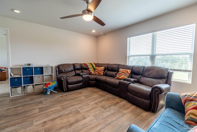 living room featuring a textured ceiling, ceiling fan, and wood-type flooring