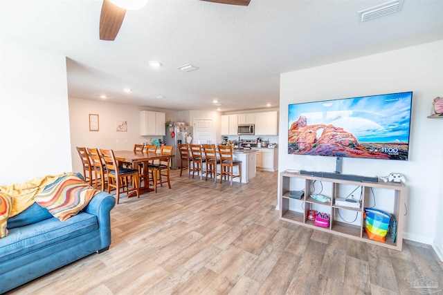 living room with light wood-type flooring and ceiling fan