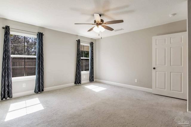 empty room with light carpet, ceiling fan, visible vents, and baseboards