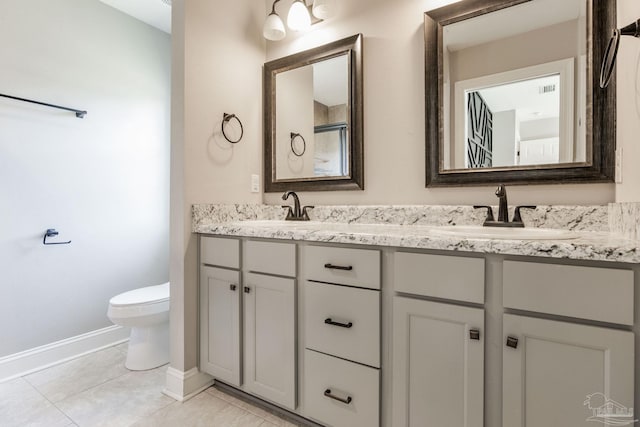 bathroom with double vanity, baseboards, toilet, and a sink