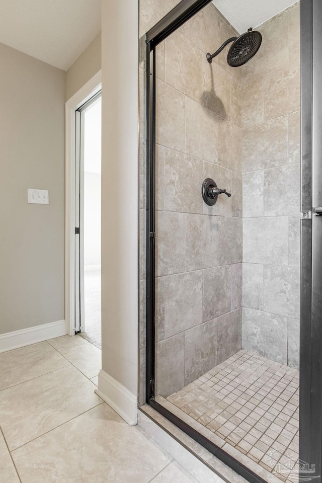 full bathroom with a stall shower, tile patterned floors, and baseboards