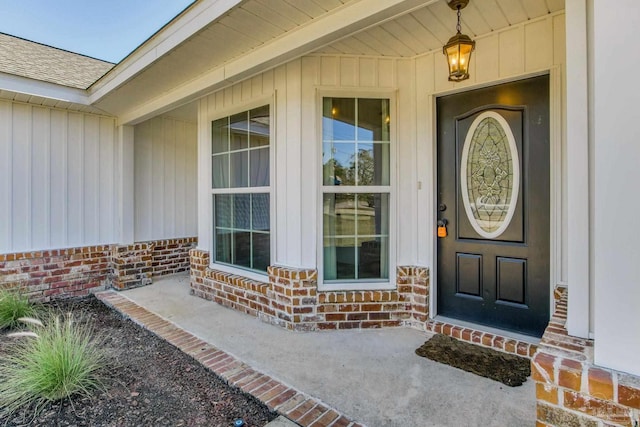 property entrance featuring a shingled roof and brick siding