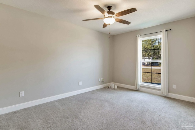 carpeted empty room featuring a ceiling fan and baseboards