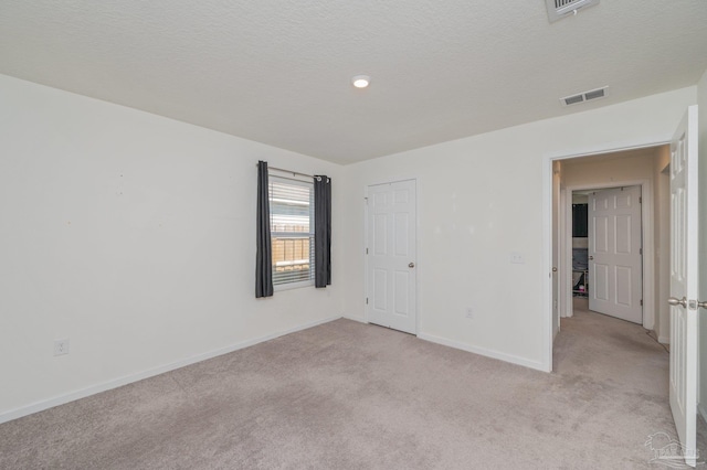 unfurnished bedroom with visible vents, light carpet, baseboards, and a textured ceiling