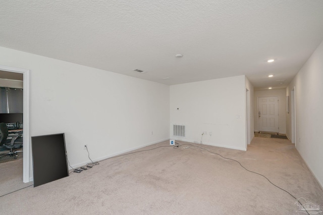 unfurnished room with visible vents, light carpet, and a textured ceiling