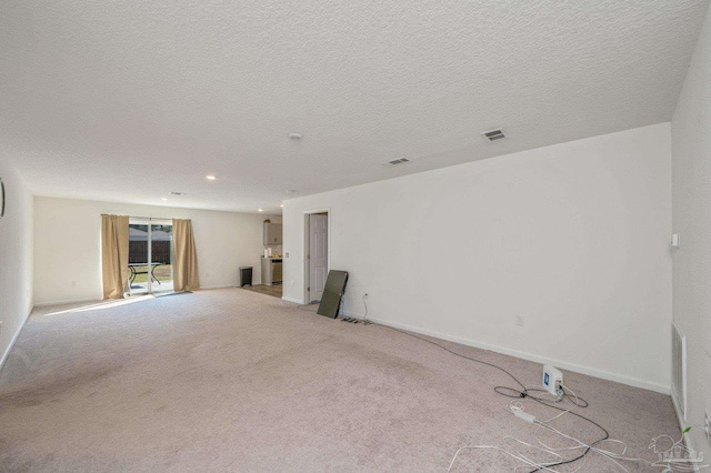 unfurnished room with light carpet, a textured ceiling, visible vents, and baseboards