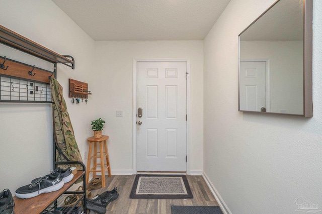 doorway featuring baseboards and wood finished floors