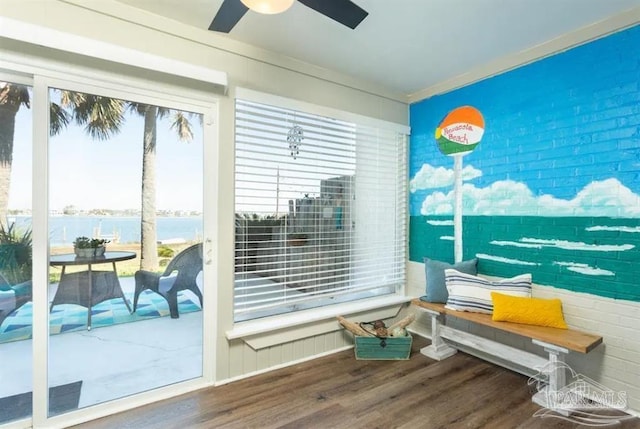 interior space featuring ceiling fan, a water view, ornamental molding, and hardwood / wood-style flooring