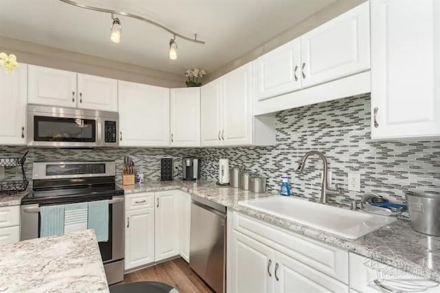 kitchen featuring stainless steel appliances, white cabinets, decorative backsplash, and sink