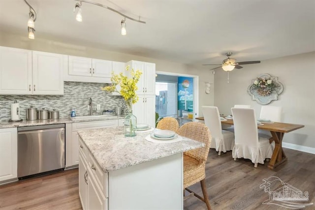 kitchen featuring sink, white cabinets, a center island, dishwasher, and light stone countertops