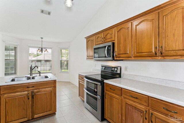 4803 Jaimee Leigh Dr, Milton, FL 32570 - kitchen featuring appliances with stainless steel finishes, a sink, light tile patterned flooring, brown cabinets, and lofted ceiling
