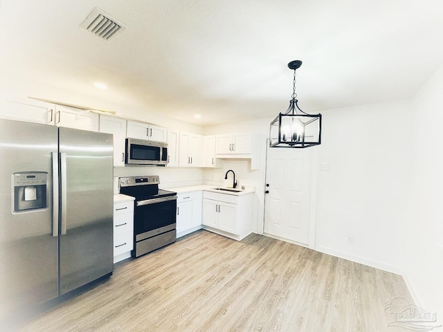 kitchen featuring hanging light fixtures, white cabinetry, sink, and stainless steel appliances