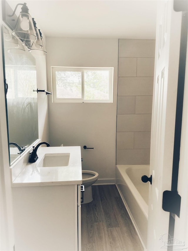 full bathroom featuring hardwood / wood-style floors, vanity, toilet, and tiled shower / bath