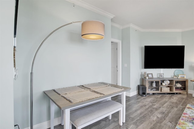 dining room featuring wood finished floors, baseboards, and ornamental molding