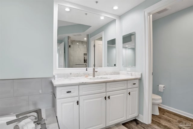 bathroom with a stall shower, wood finished floors, toilet, vanity, and recessed lighting